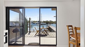 A sliding glass door leading to an outdoor deck with a view of a marina and boats. - Skippers Landing- On the water with private jetty (Lemon Tree Passage)