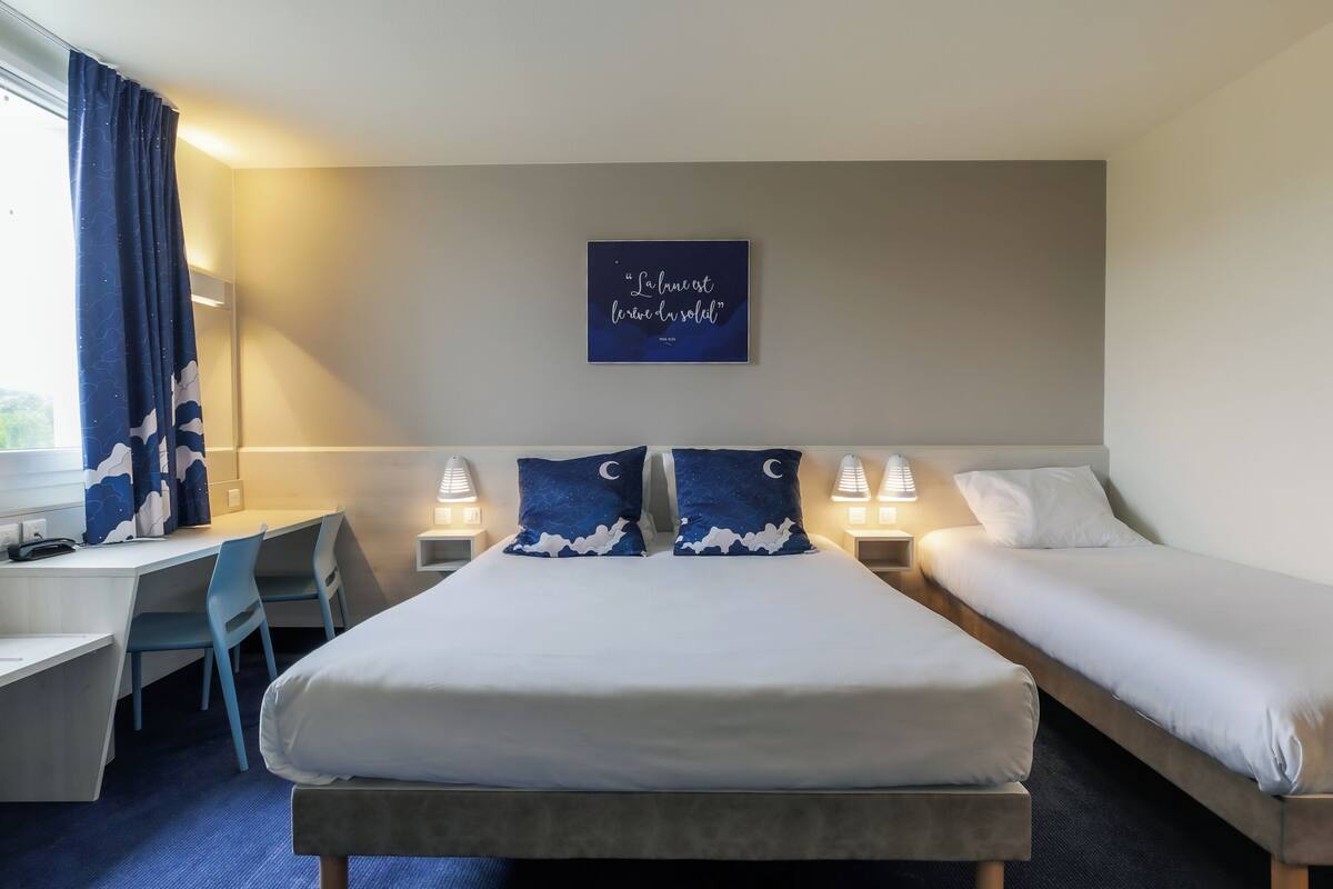Une chambre d’hôtel comprenant un lit, deux tables de chevet avec des lampes, un bureau et une chaise.