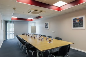 Conference room with a long table, black chairs, and a red accent wall.