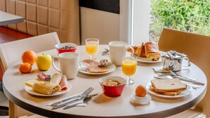 A breakfast table with various food items, including toast, eggs, and juice. - ACE Hôtel Thionville Porte du Luxembourg (Thionville)