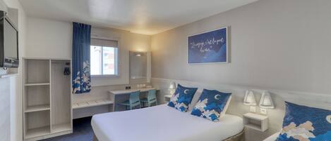 A hotel room with a bed, bedside lamps, a desk, a chair, a wardrobe, and a window with curtains.