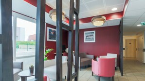 A modern lobby with red walls, white and pink seating, and artwork on the walls. - ACE Hôtel Thionville Porte du Luxembourg (Thionville)