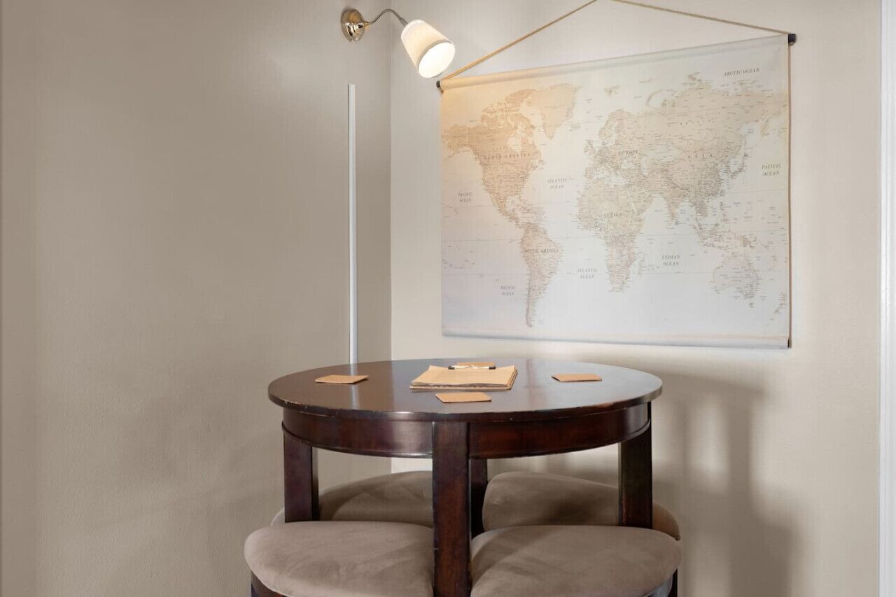 A round wooden table with a world map on the wall behind it.