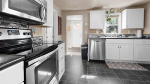 Une cuisine moderne dotée d’appareils électroménagers en acier inoxydable, de meubles blancs et d’un sol carrelé.
