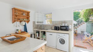 Eine kleine Küche mit Waschmaschine, Mikrowelle und einer Holzkammer.