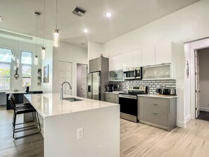 A modern kitchen with stainless steel appliances, a large island, and pendant lighting.