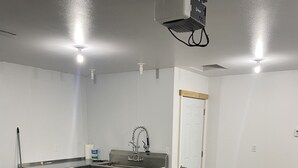 A kitchen with a stainless steel sink, a red bucket, and a white door. - Brand New Duplex Across the road from Devils Lake w/lake access (Warwick)