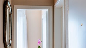 Ein Flur mit dekorativer Decke, einem Spiegel, einer Tür und einem kleinen Tisch mit einem Blumentopf.