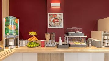 Una barra de desayuno con una exhibición de frutas, un dispensador de zumo y una máquina de café.