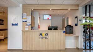 Un mostrador de recepción de hotel con encimera de madera, una pantalla digital y señal de accesibilidad para sillas de ruedas.