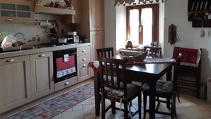 A kitchen with wooden cabinets, a stove, and a dining area with a table and chairs. - Romantic house with swimming pool near Bologna & Florence CIN: IT047018C2OXJNJAB8 (Treppio)
