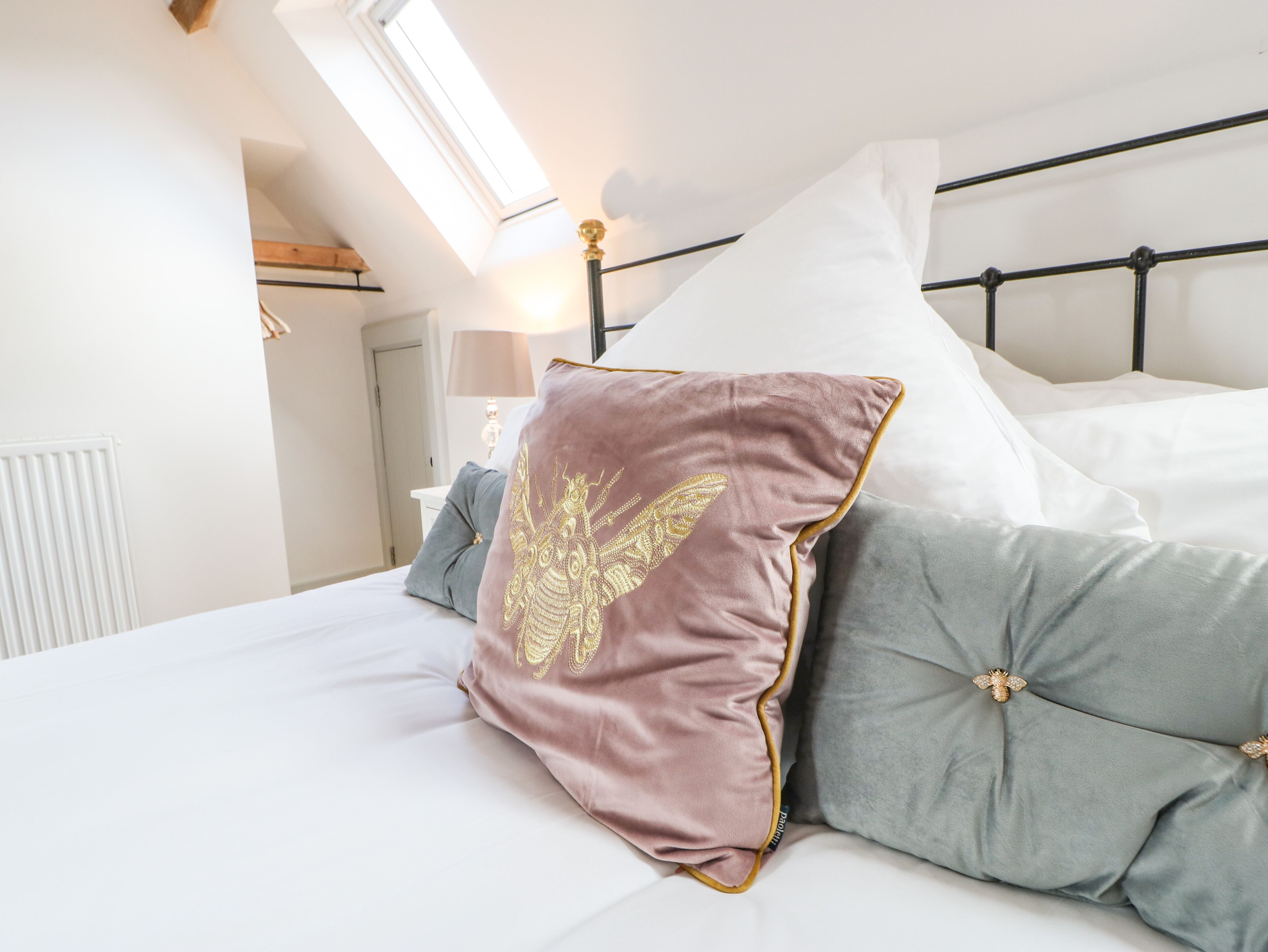 A neatly made bed with a headboard, pillows, and a bedside lamp.