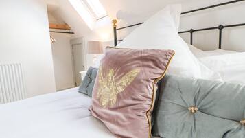 A neatly made bed with a headboard, pillows, and a bedside lamp.