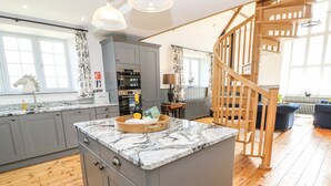 Une cuisine moderne avec des meubles gris, un plan de travail en marbre et un îlot central en bois.