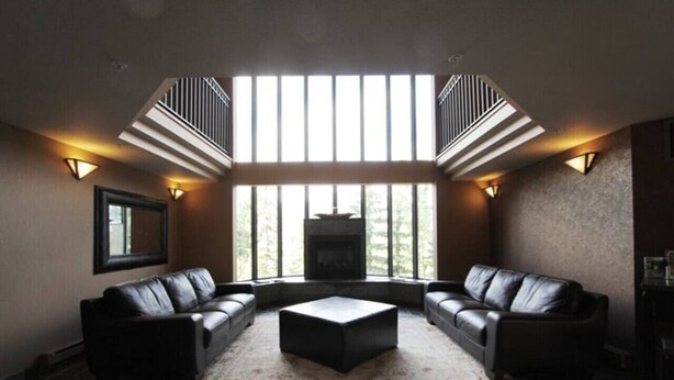 A modern living room with a fireplace, leather sofas, and a large window. - Mountainside 1BR: Sleeps 4, Pool, Hot tub & Private Balcony - Walk to Everything! (Whistler)