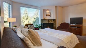 A bedroom with a bed, a TV, a fireplace, and a window with blinds. - Mountainside 1BR: Sleeps 4, Pool, Hot tub & Private Balcony - Walk to Everything! (Whistler)