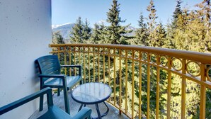 A balcony with a yellow railing, two chairs, and a small table. - Mountainside 1BR: Sleeps 4, Pool, Hot tub & Private Balcony - Walk to Everything! (Whistler)