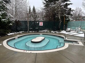 Ein Schwimmbecken mit einem Schild, das das Tauchen verbietet, umgeben von schneebedeckten Bäumen und einem eingezäunten Bereich.