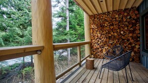 A wooden deck with a chair and a stack of firewood.