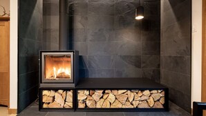 A modern fireplace with a stone base, a visible fire, and a hanging light fixture.