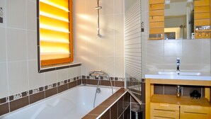 A modern bathroom with a bathtub, a vanity with a mirror, and a window with blinds. - La Grange, Architect's house in the heart of Périgord (Sorges)