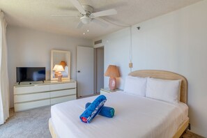 Habitación de hotel con cama, televisor en una cómoda, ventilador de techo y lámpara.