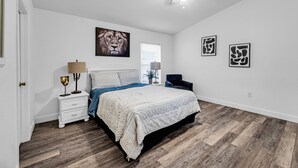 A bedroom with a bed, nightstand, lamp, ceiling fan, and artwork on the walls. - Sunshine & Splash + Disney area pool home (Davenport)