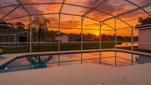 A swimming pool with a view of a sunset through a metal structure. - Sunshine & Splash + Disney area pool home (Davenport)