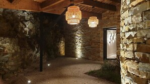 Un estrecho pasillo de piedra con lámparas de mimbre colgantes, que conduce a una puerta con un cartel.