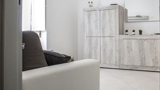 Un salon moderne avec un canapé gris et un meuble blanc en arrière-plan.