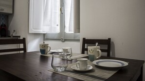 Une table à manger avec quelques tasses vides et une assiette, une fenêtre avec des rideaux et une chaise.