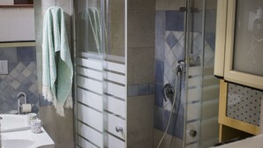 Une salle de bain avec une douche à parois de verre, un lavabo avec un miroir et une serviette accrochée au mur.