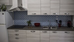 Une cuisine avec un crédence à motifs, un évier en acier inoxydable et un réfrigérateur blanc.
