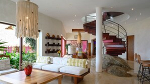 A spacious living area with a modern staircase, a large sofa, and a dining table.