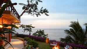 A patio with a fire pit, outdoor seating, and a view of the ocean.