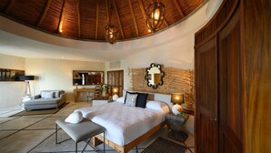 A spacious bedroom with a large bed, a wooden wardrobe, and a curved ceiling.