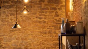 A cozy room with a stone wall, a wooden ceiling, and a sofa with cushions. There are pendant lights hanging from the ceiling. - 3 gîtes, swimming pool, 6 bd / 13 p - Puy du Fou / Marais poitevin / Mervent / Vouvant (Rives du Fougerais)
