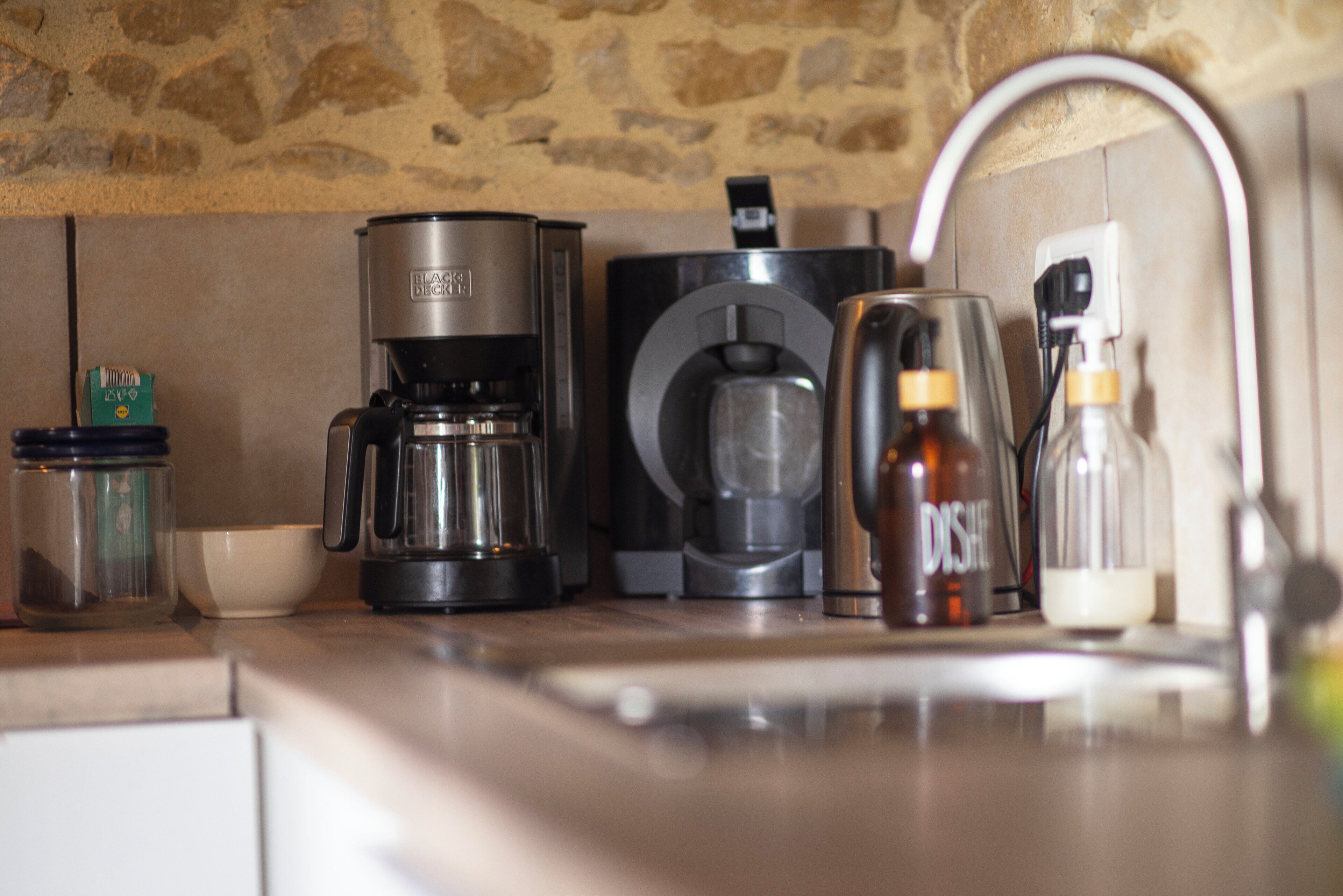 A kitchen with a coffee maker, a blender, and a coffee machine.