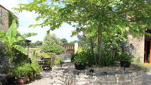 A stone well surrounded by potted plants and a rustic outdoor seating area. - 3 gîtes, swimming pool, 6 bd / 13 p - Puy du Fou / Marais poitevin / Mervent / Vouvant (Rives du Fougerais)