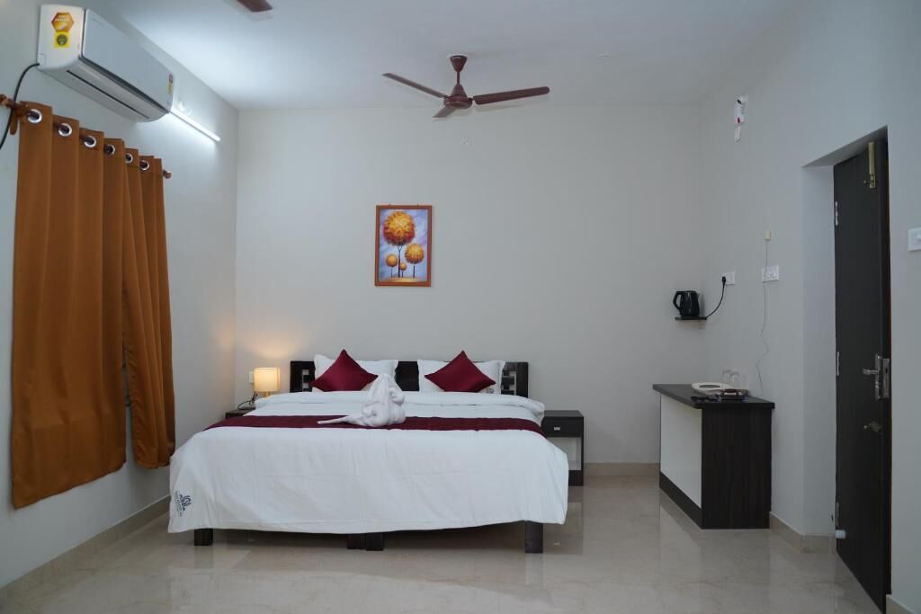 A hotel room with a bed, a nightstand, a desk, an air conditioner, a ceiling fan, and a painting on the wall.