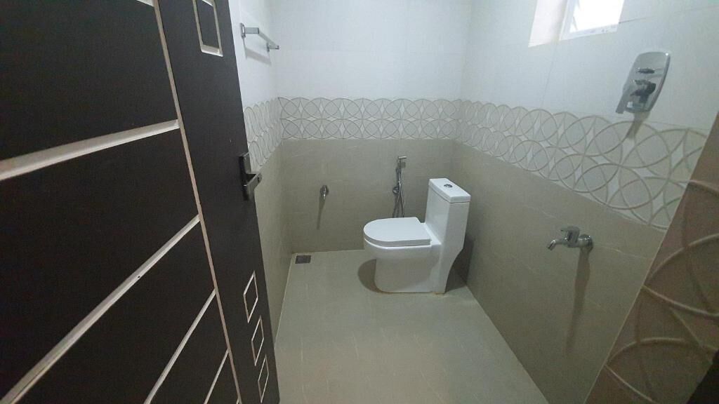 Un baño pequeño y funcional con inodoro, ducha y secamanos.