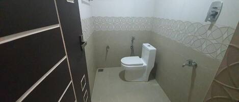 Un baño pequeño y funcional con inodoro, ducha y secamanos.