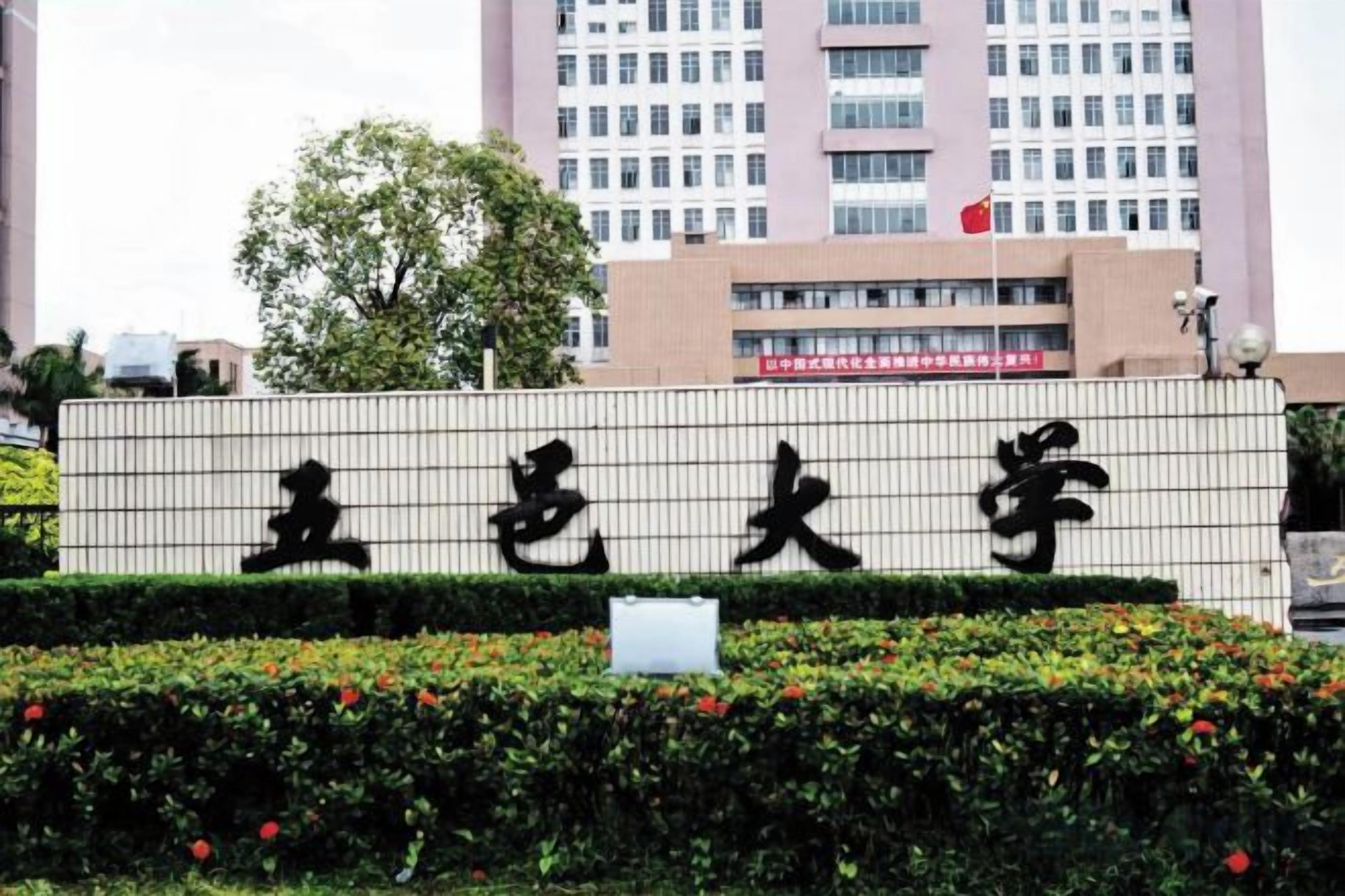 A sign with Chinese characters, a building in the background, and a tree.