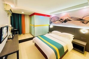 A hotel room with a bed, a desk with a computer, a TV, and a wall-mounted artwork. - Jiangmen Danxia Hotel (Jiangmen)