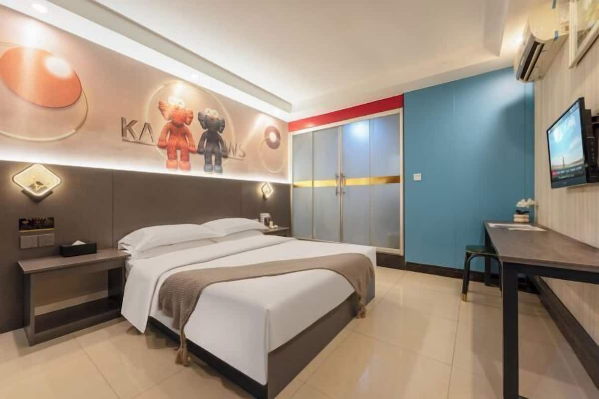 Una habitación de hotel moderna con una cama grande, un escritorio, un televisor y un armario.