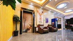 A hotel lobby with a reception desk, seating area, and a large poster on the wall. - Jiangmen Danxia Hotel (Jiangmen)