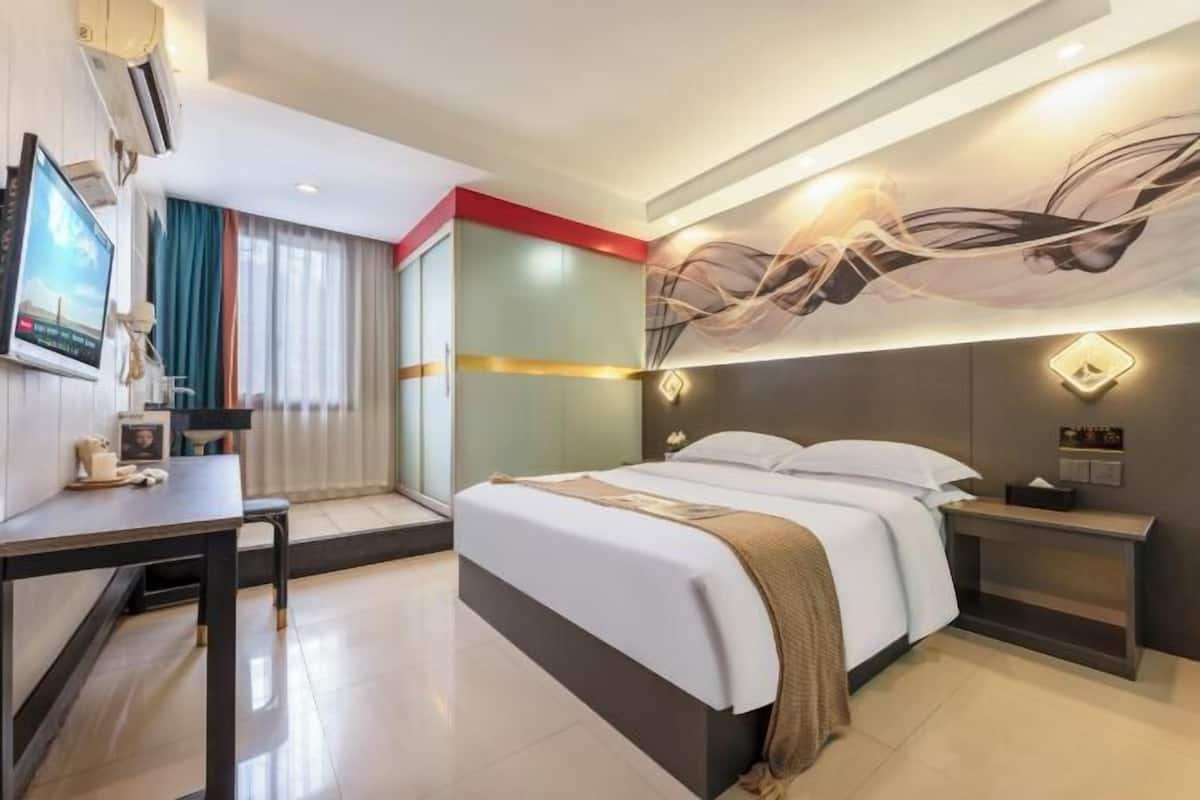 Una habitación de hotel moderna con una cama, mesitas de noche, un televisor y una gran obra de arte abstracta en la pared.