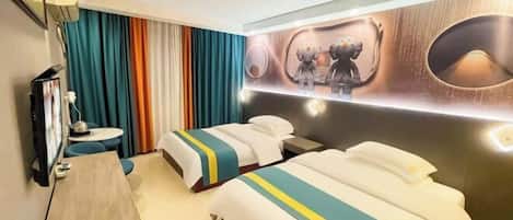 Habitación de hotel con dos camas, un escritorio, una silla, un televisor y una pared decorada con un espejo y obras de arte.