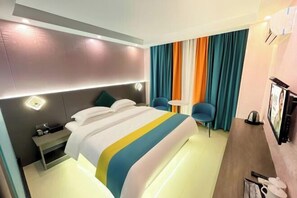 A hotel room with a bed, bedside table, chair, and a TV. - Jiangmen Danxia Hotel (Jiangmen)
