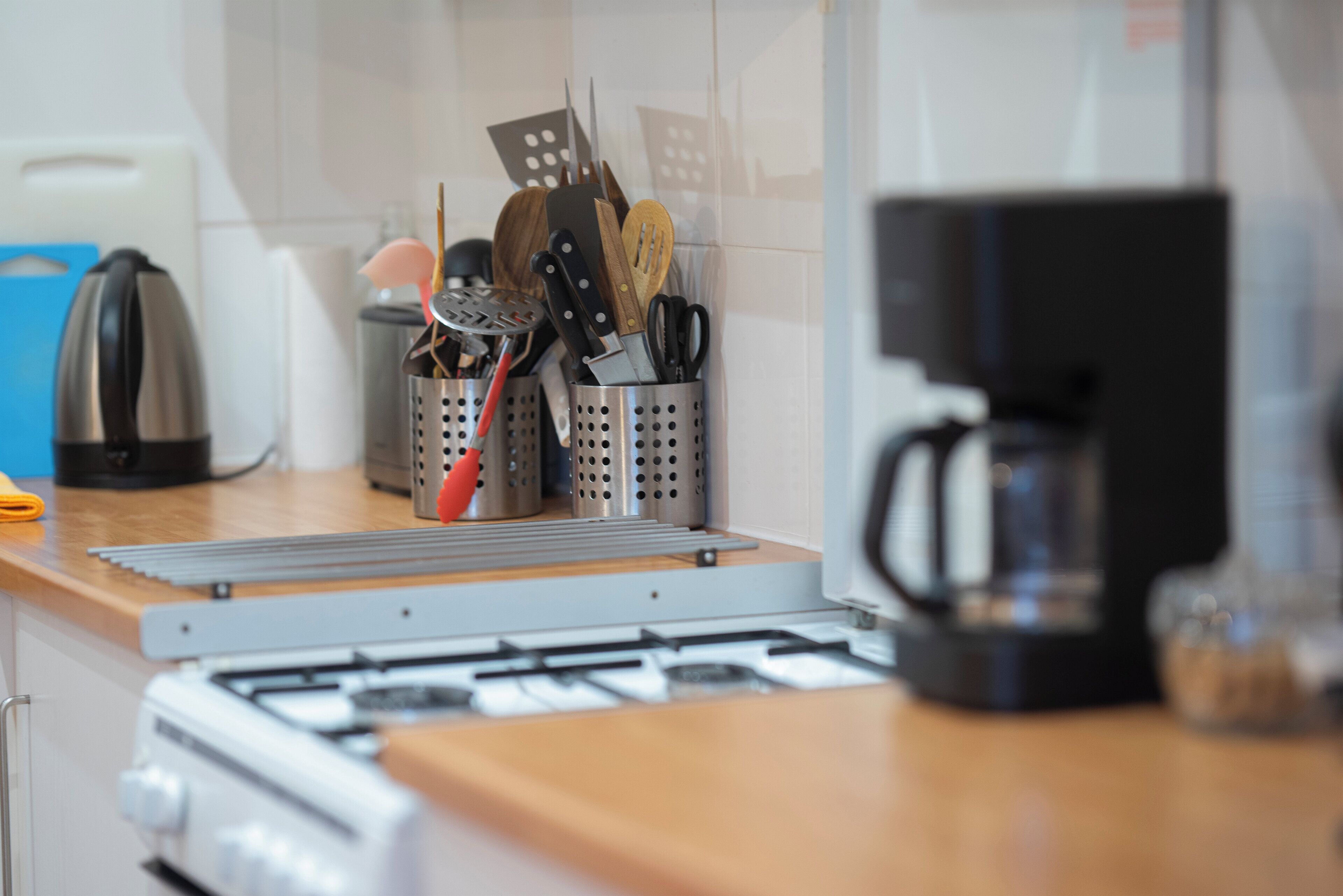A kitchen with a gas stove, a coffee maker, and various utensils in holders.